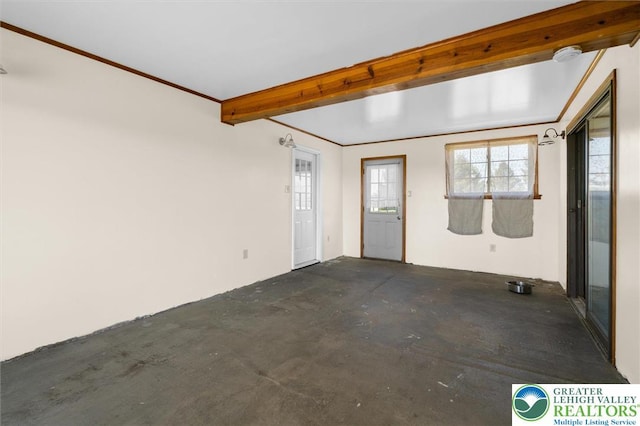 empty room with concrete flooring and beamed ceiling