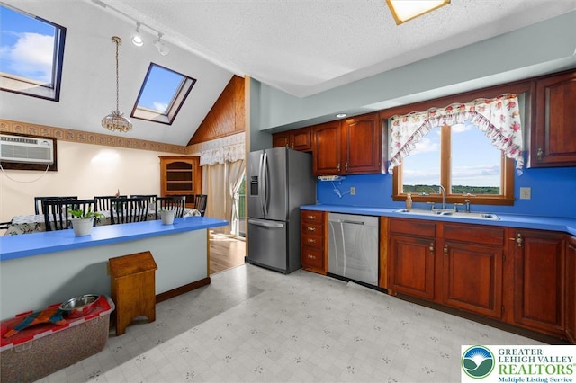 kitchen with appliances with stainless steel finishes, a sink, light floors, a skylight, and a wall mounted AC