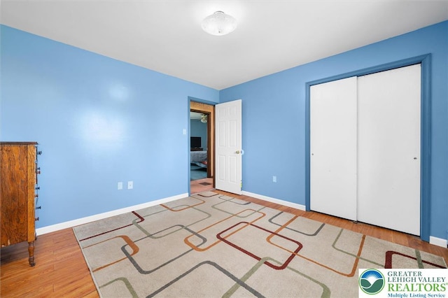unfurnished bedroom with baseboards, a closet, and wood finished floors