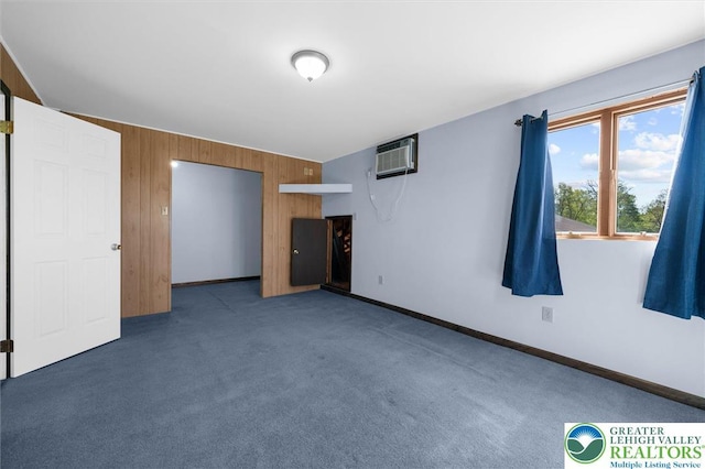 interior space featuring carpet floors, baseboards, an AC wall unit, and wood walls