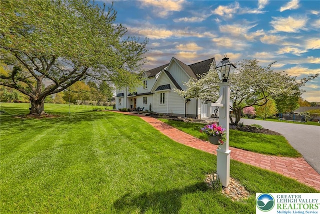 property exterior at dusk featuring a lawn and a chimney