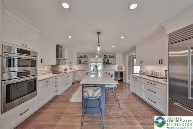 kitchen with open shelves, wall chimney exhaust hood, white cabinets, and stainless steel appliances