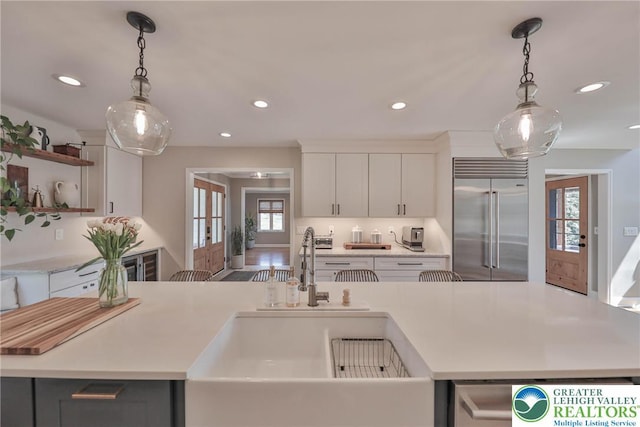 kitchen featuring light countertops, recessed lighting, stainless steel built in fridge, and a sink
