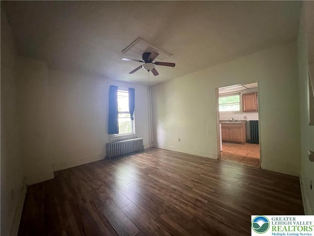 spare room with a ceiling fan, radiator heating unit, and light wood-style floors
