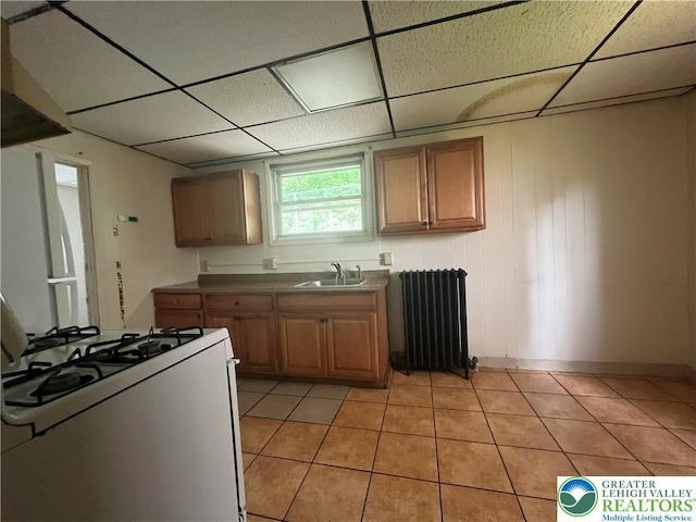 kitchen featuring radiator, gas range gas stove, and a drop ceiling