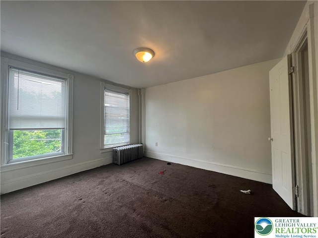 unfurnished bedroom with baseboards, carpet, and radiator