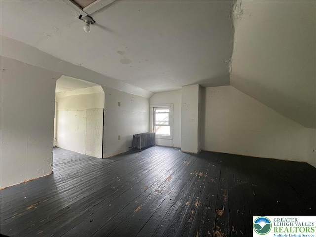 additional living space with radiator heating unit, hardwood / wood-style flooring, and lofted ceiling