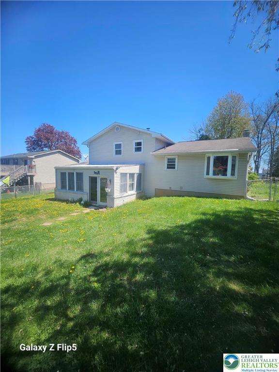 back of property featuring fence, a sunroom, and a yard