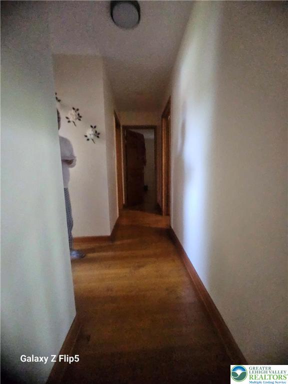 corridor with baseboards and light wood-type flooring