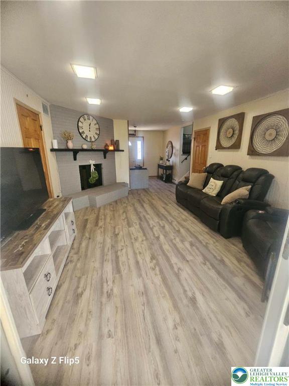 living room with light wood-style flooring and a brick fireplace