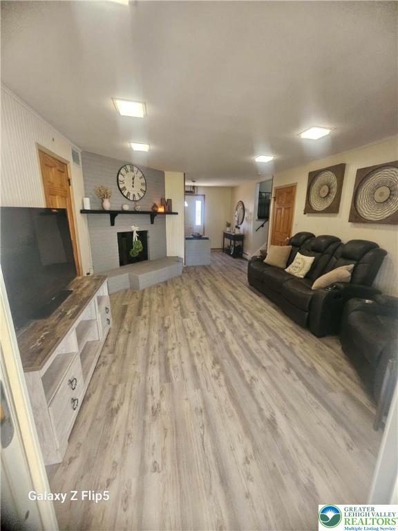 living room with light wood-style floors and a large fireplace