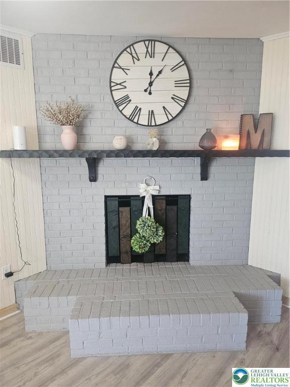interior details featuring a brick fireplace, visible vents, and wood finished floors