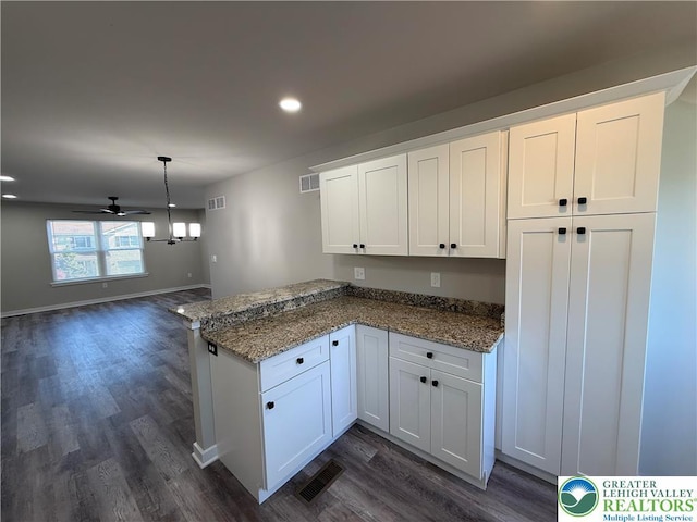 kitchen with dark wood-style flooring, a peninsula, white cabinets, and visible vents