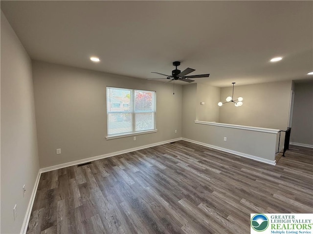 empty room with recessed lighting, baseboards, ceiling fan with notable chandelier, and dark wood-style flooring