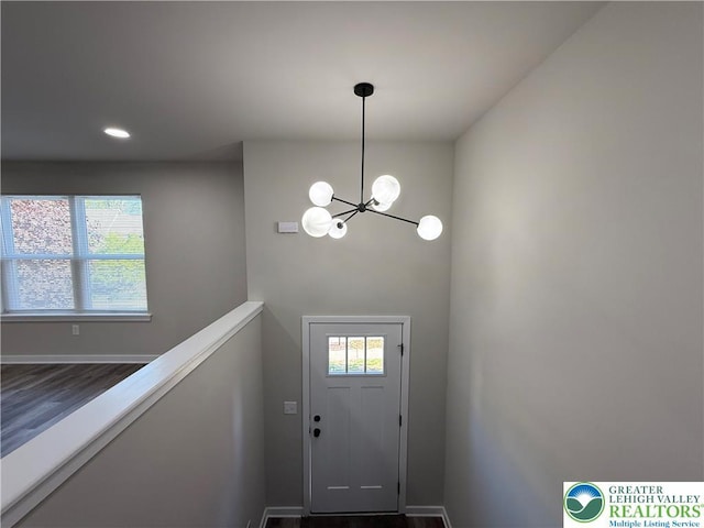 doorway to outside featuring baseboards, recessed lighting, and a chandelier