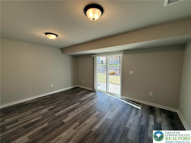 empty room with baseboards, dark wood finished floors, and visible vents