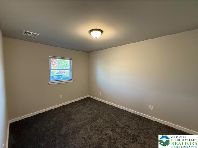 unfurnished room with visible vents, baseboards, and dark carpet