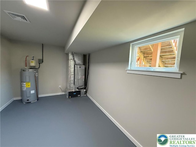 below grade area with baseboards, visible vents, heating unit, and electric water heater