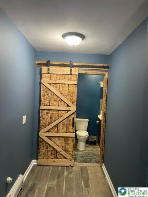 bathroom featuring baseboards, wood finished floors, baseboard heating, and toilet