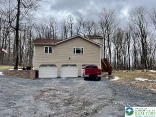 view of side of home featuring a garage and gravel driveway
