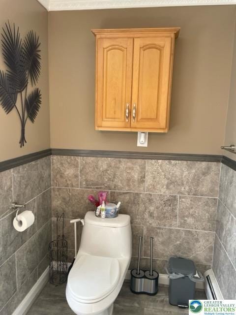 bathroom with toilet, tile walls, and wainscoting