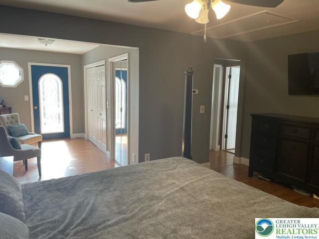 bedroom featuring baseboards, ceiling fan, wood finished floors, and attic access