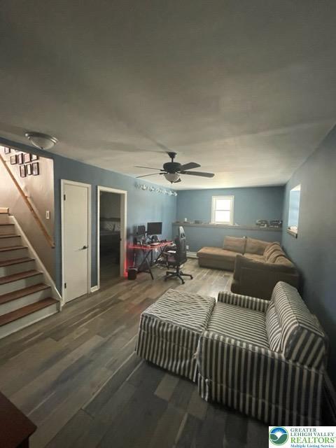 living room with stairs, ceiling fan, and wood finished floors
