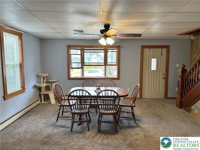 carpeted dining room with visible vents, a ceiling fan, stairs, a paneled ceiling, and a baseboard radiator