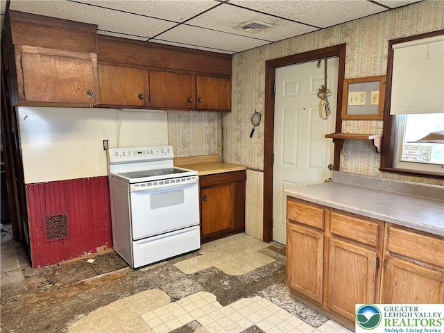 kitchen featuring white electric range, light floors, brown cabinets, and visible vents