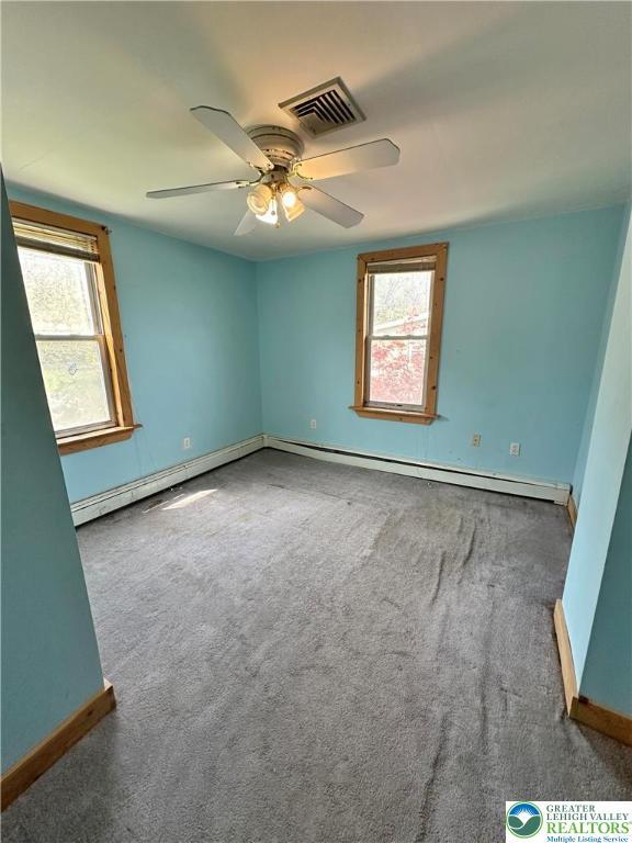 spare room featuring visible vents, baseboards, a baseboard heating unit, and a healthy amount of sunlight