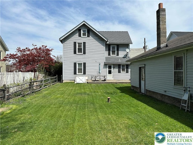 rear view of house featuring fence and a yard