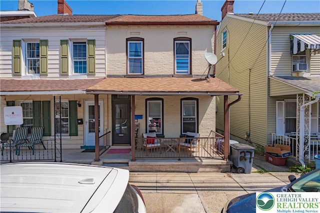 view of front of property with a porch, cooling unit, and a chimney