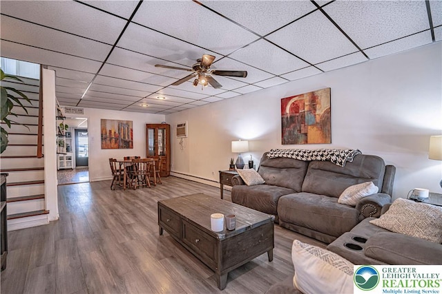 living area featuring baseboard heating, a paneled ceiling, a ceiling fan, baseboards, and wood finished floors