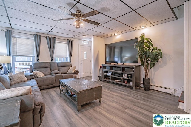 living area featuring wood finished floors, baseboards, a baseboard radiator, a paneled ceiling, and a ceiling fan