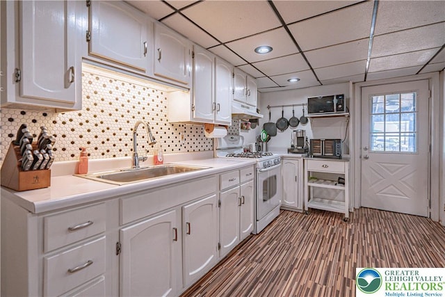 kitchen featuring a sink, light countertops, gas range gas stove, white cabinetry, and under cabinet range hood