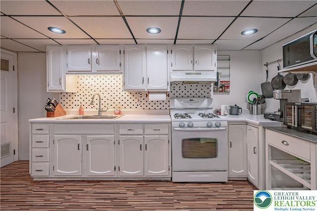 kitchen with a sink, a drop ceiling, wood finished floors, under cabinet range hood, and white range with gas cooktop