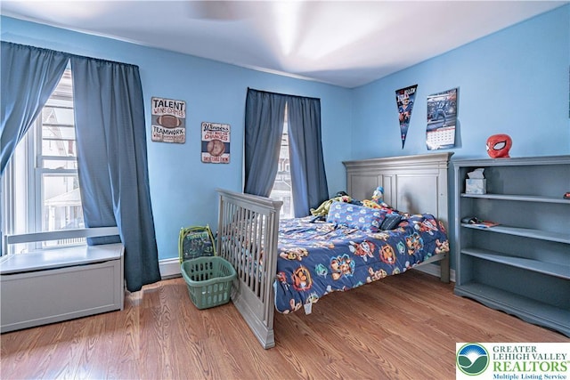 bedroom featuring a baseboard heating unit and wood finished floors
