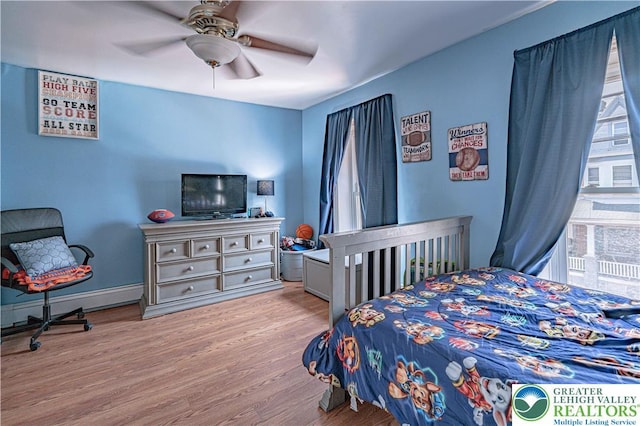 bedroom featuring baseboards, a baseboard radiator, ceiling fan, and wood finished floors