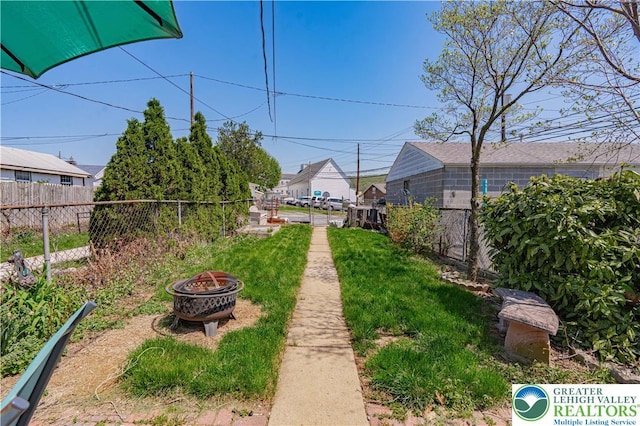 view of yard with fence and an outdoor fire pit