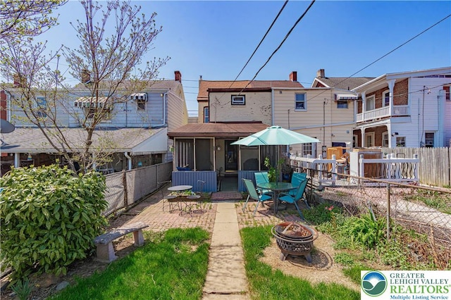 rear view of house featuring a patio, a fire pit, a fenced backyard, and a sunroom