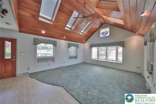 unfurnished living room with vaulted ceiling with skylight, wood ceiling, a ceiling fan, visible vents, and baseboards