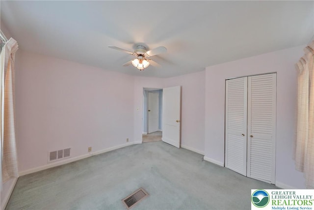 unfurnished bedroom featuring visible vents, baseboards, a closet, and light carpet