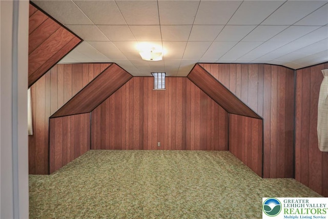 bonus room featuring carpet flooring and wood walls