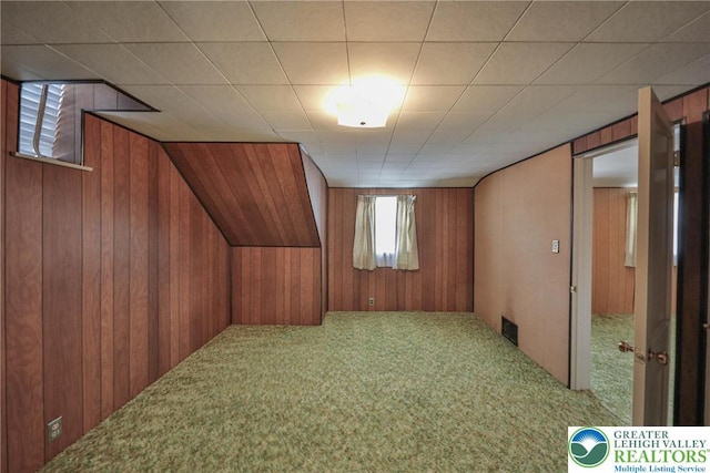 bonus room with wooden walls, carpet flooring, and visible vents