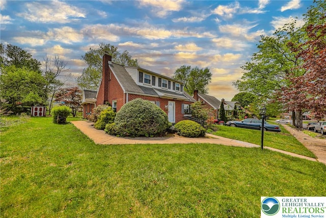 view of front facade featuring brick siding, a chimney, and a front lawn