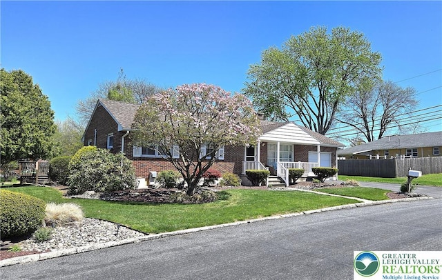 view of front of property featuring covered porch, a chimney, brick siding, fence, and a front lawn