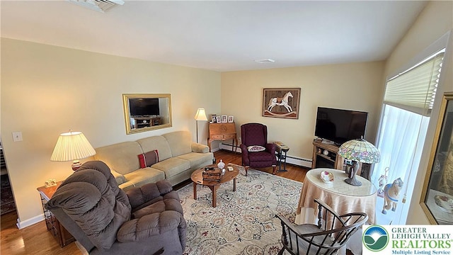 living area featuring baseboard heating, baseboards, wood finished floors, a baseboard radiator, and visible vents