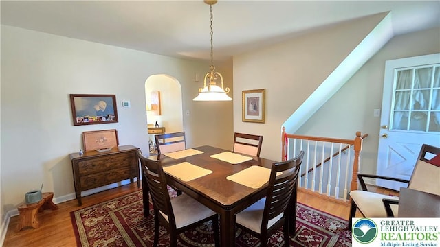 dining area with arched walkways and wood finished floors