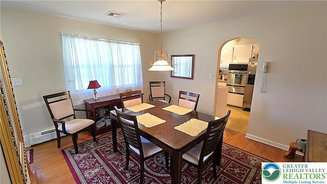 dining room with light wood-type flooring, arched walkways, baseboards, and visible vents