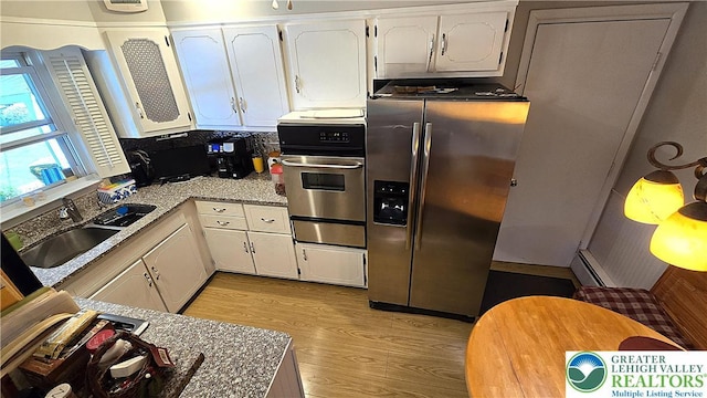 kitchen featuring white cabinets, stainless steel appliances, a sink, and light wood-type flooring